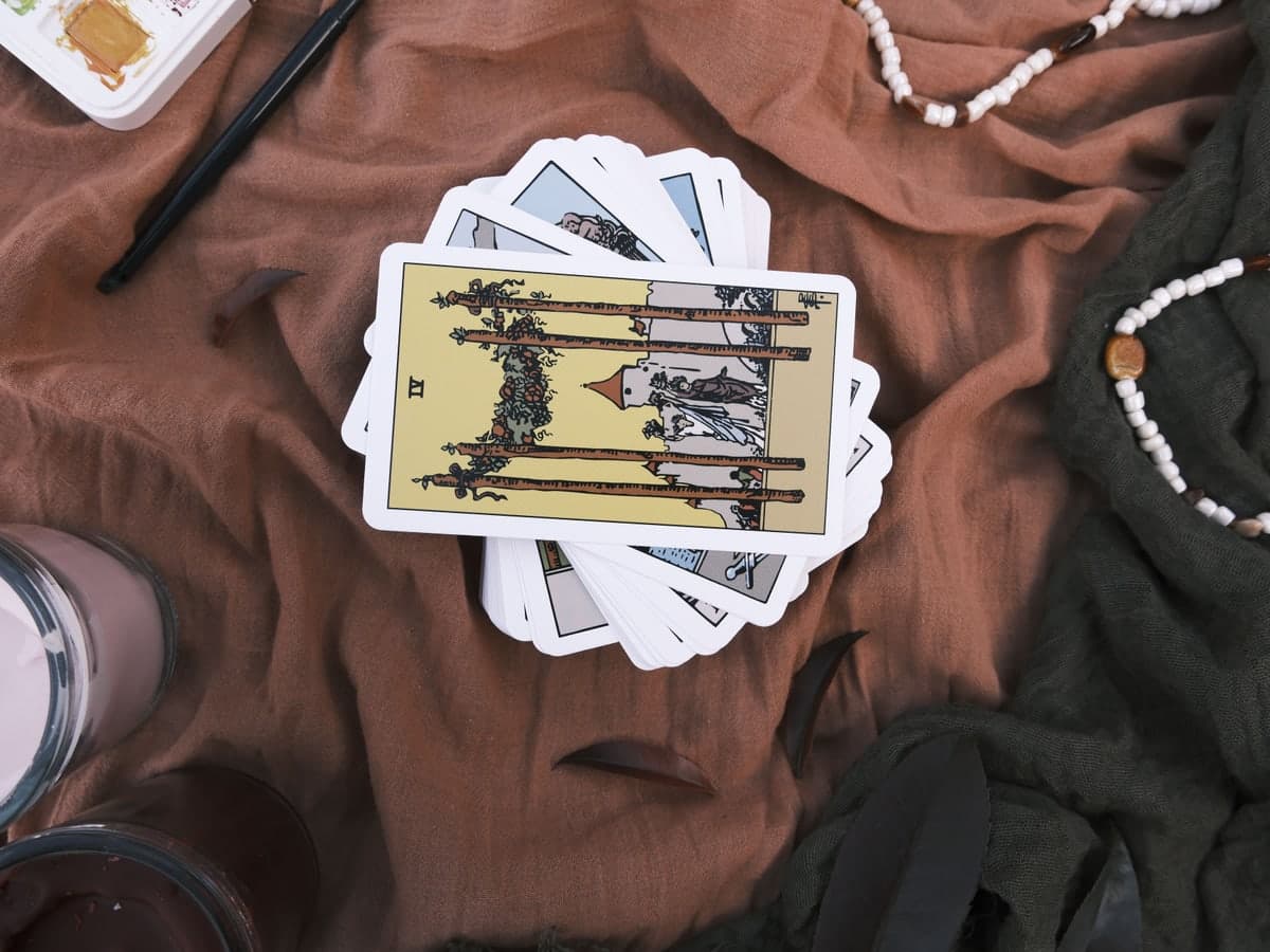 Tarot cards spread beside a laptop on a reader's desk